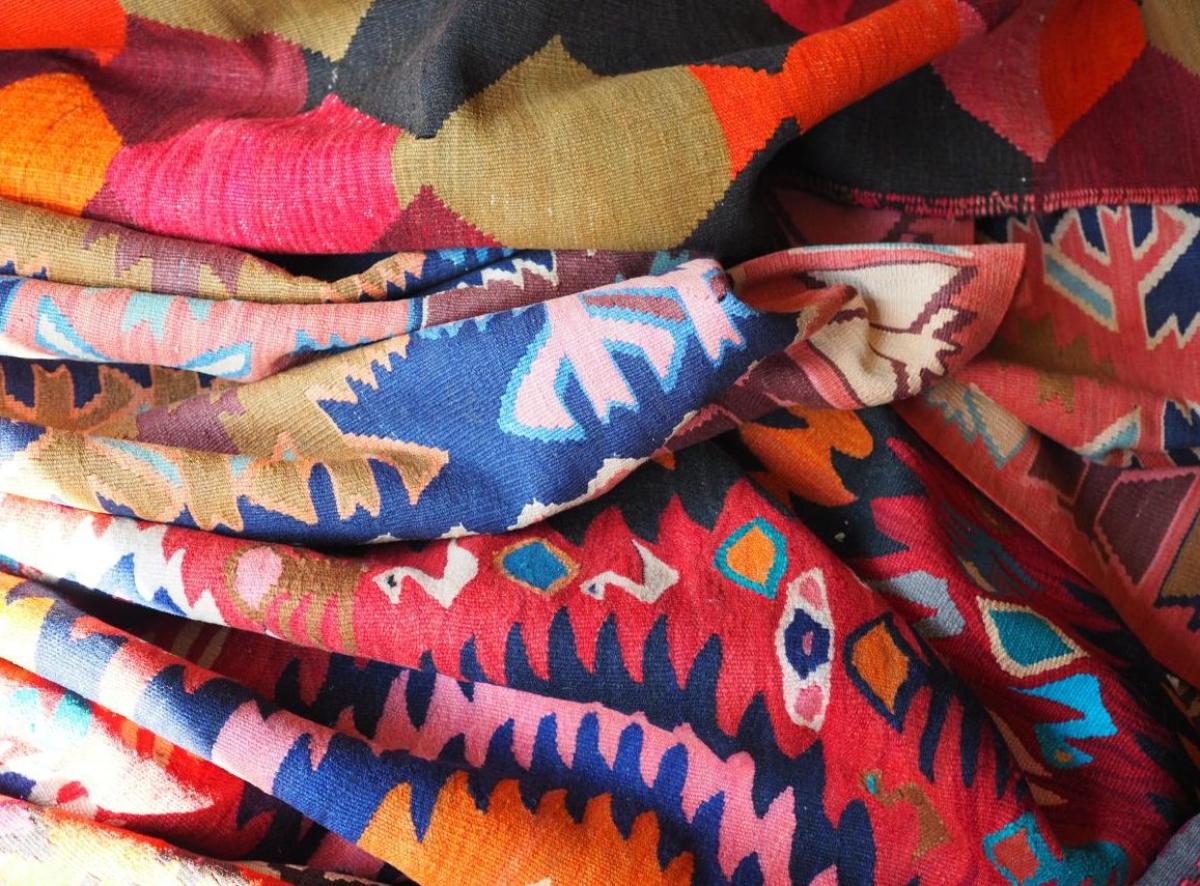 Close-up of a folded kilim rug in shades of blue, red, and orange with traditional geometric pattern